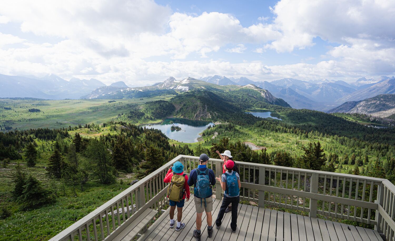 Four people on the Standish Viewing Deck at sunshine Meadows overlooking Rockbound Lake near Banff National Park.